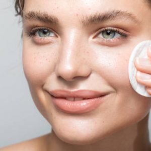 Close up studio shot of a beautiful woman with perfect skin, while she cleaning her face